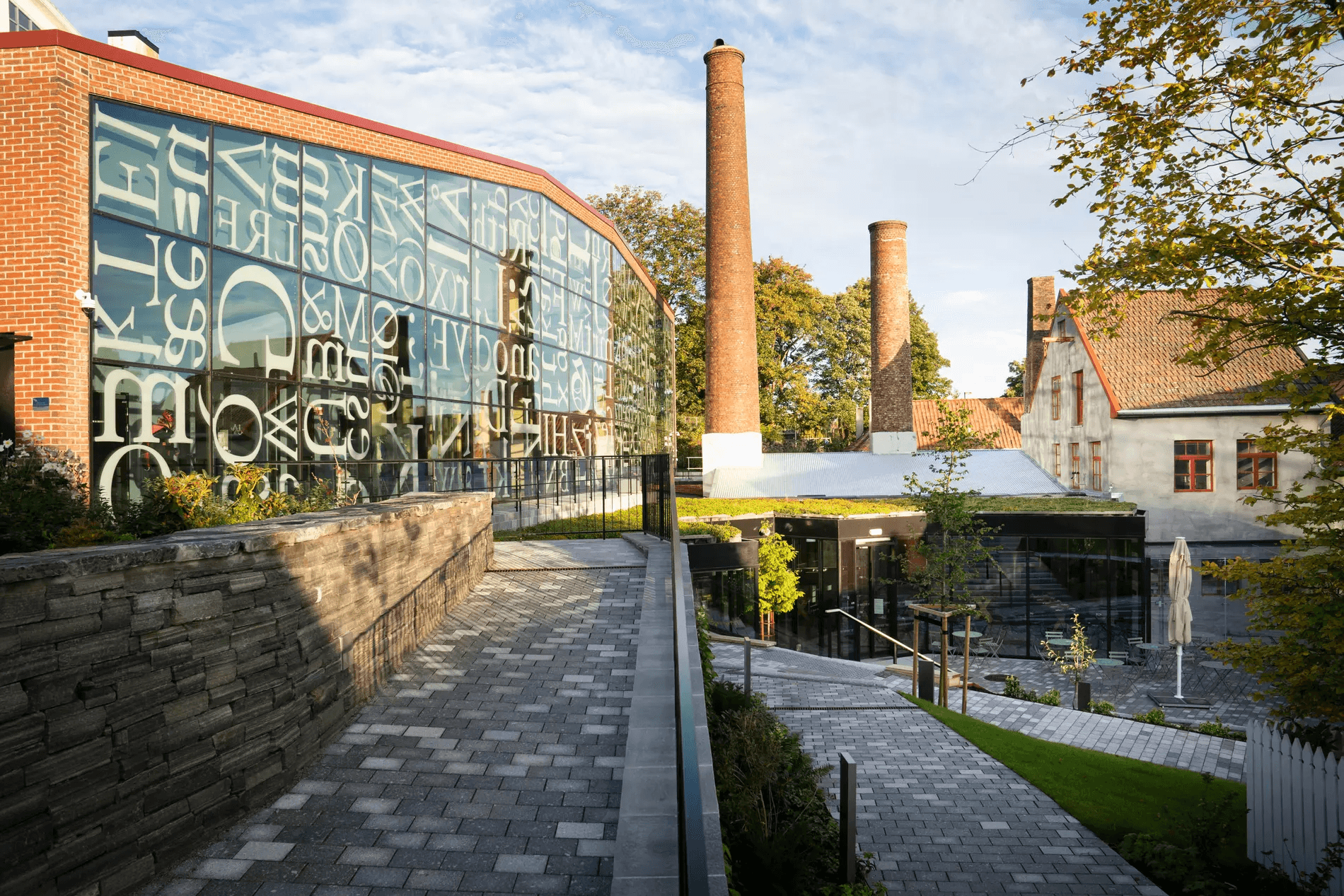 Norwegian Printing Museum exterior featuring typographic glass facade and historic chimney