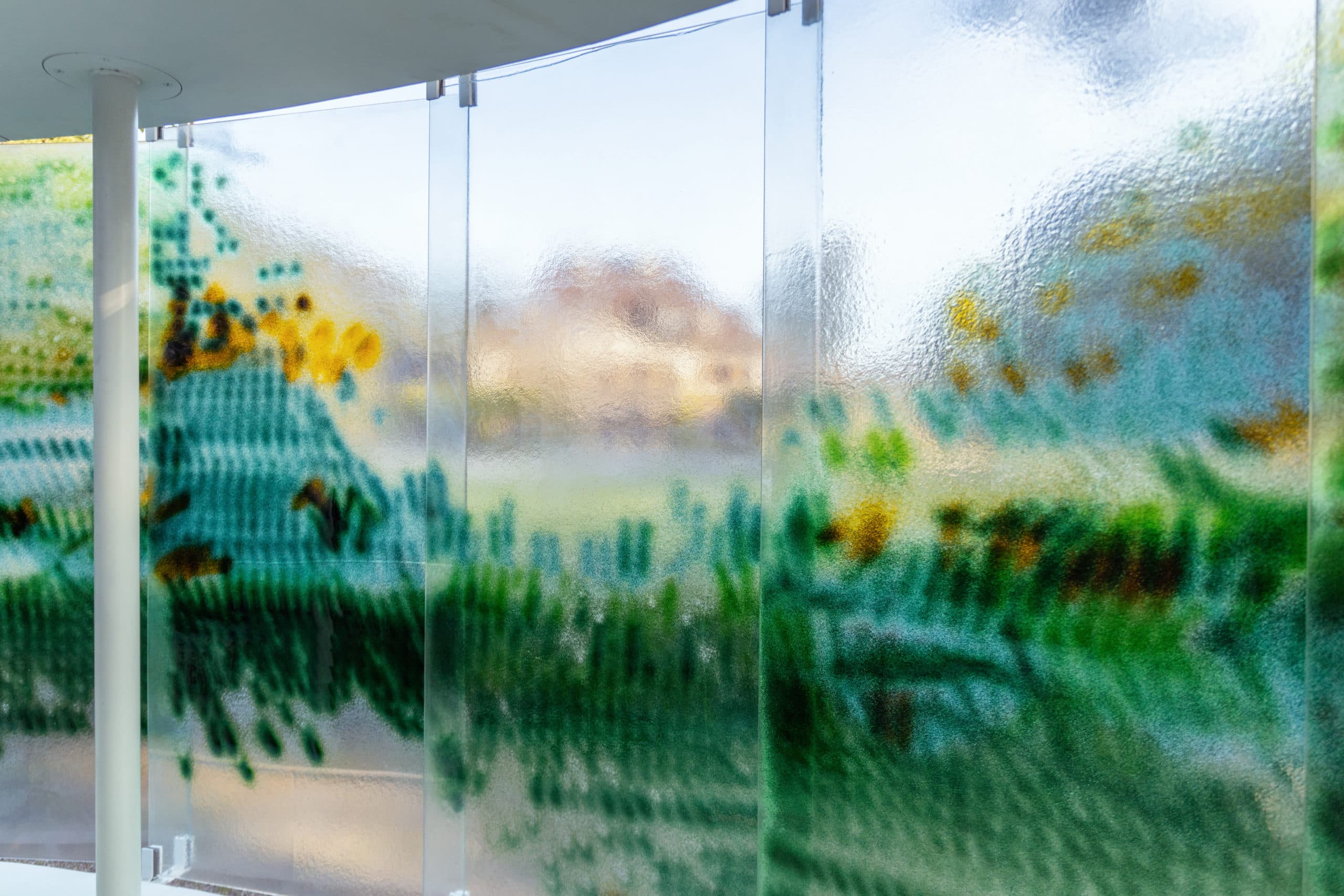 Interior viewpoint through colored glass panels looking out to the park