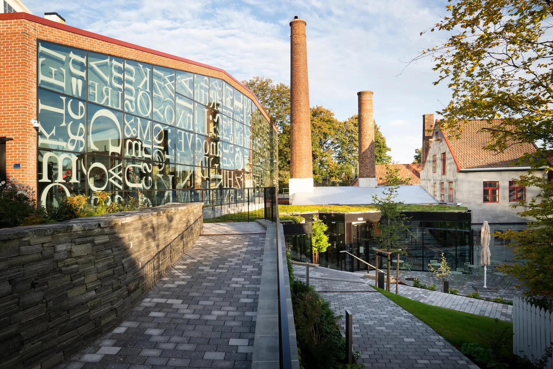 Norwegian Printing Museum exterior featuring typographic glass facade and historic chimney